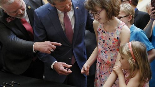After the signing a bill to allow the in-state cultivation and manufacture of a marijuana oil for medical purposes, Gov. Brian Kemp, with the bill’s author, state Rep. Micah Gravley, R-Douglasville, gave a ceremonial pen to 13-year-old Alaina Cloud. Alaina, who has a severe form of epilepsy that causes uncontrollable seizures, was joined by her sister, Courtney, 5. Kemp, joined by medical marijuana users and advocates, signed HB 324, which will also allow medical marijuana oil to be sold in Georgia for the first time. Bob Andres / bandres@ajc.com