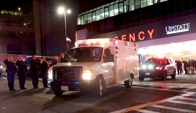 Transport ambulances carry the bodies of two slain officers to the Wally Howard Forensics Science Center in Syracuse, N.Y. early Monday morning, April 15, 2024. Police officers from several local agencies gathered at Upstate hospital's emergency room to hear the news of two slain officers. (Dennis Nett/The Post-Standard via AP)