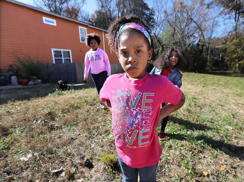 Rosario Hernandez’s granddaughters Aryanna Maymi Booker (from left), 11, Ava Booker, 5, and Aniyah Royal, 9, stand on the vacant lot next to her home where they played and gardened near Mercedes-Benz Stadium on Nov. 25, 2019, in Atlanta. Hernandez discovered slag, a byproduct of smelting, on the property. CURTIS COMPTON / CCOMPTON@AJC.COM