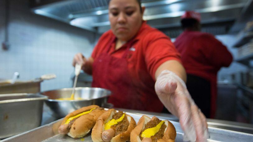 A woman makes chili dogs at The Varsity in downtown Atlanta. Now the chain’s owners are contemplating big changes. BRANDEN CAMP/SPECIAL