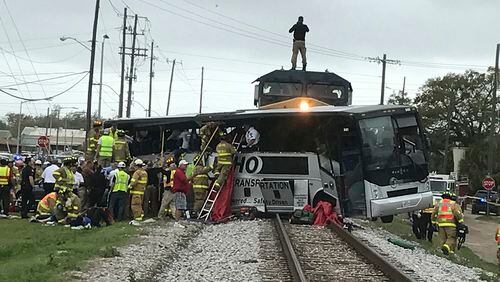 Biloxi firefighters assist injured passengers after their charter bus collided with a train in Biloxi, Miss., Tuesday, March 7, 2017. Biloxi city spokesman Vincent Creel says emergency responders were still removing injured people from the bus more than 30 minutes after the crash. (John Fitzhugh/Sun Herald via AP)