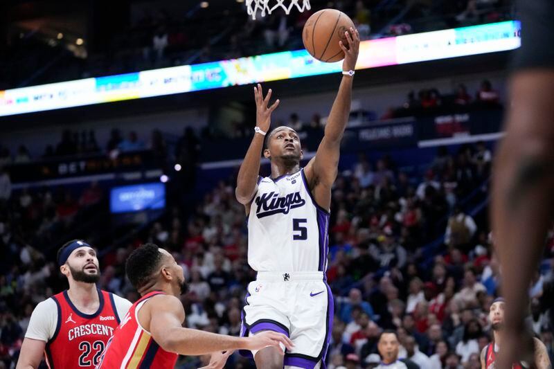 Sacramento Kings guard De'Aaron Fox (5) goes to the basket over New Orleans Pelicans guard CJ McCollum and forward Larry Nance Jr. (22) in the first half of an NBA basketball play-in tournament game in New Orleans, Friday, April 19, 2024. (AP Photo/Gerald Herbert)