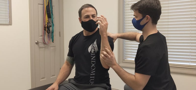 Johns Creek chiropractor Chandler Turnipseed, right, who says he is an evidence-based chiropractor who has taken a COVID vaccine himself, performs a soft tissue treatment called active release to patient Jeremy Warner's left shoulder on Wednesday, May 12, 2021. (Contributed)