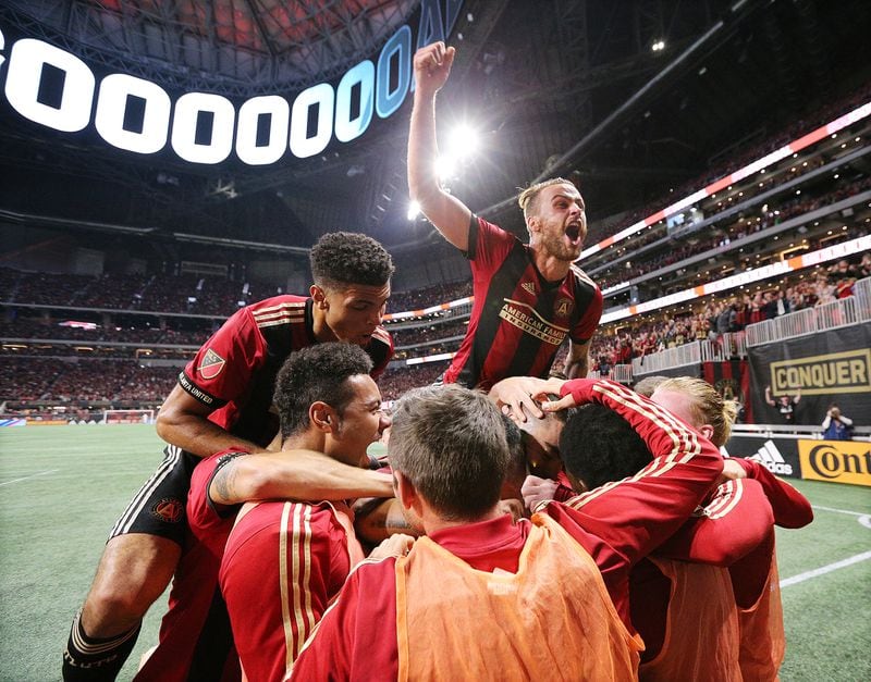 Atlanta United midfielder Miguel Almiron is mobbed by teammates after scoring his team’s second goal of the night on a penalty kick for a 2-0 lead over New York City during the first half in their MLS Eastern Conference Semifinal playoff match on Sunday, Nov. 11, 2018, in Atlanta.  Curtis Compton/ccompton@ajc.com