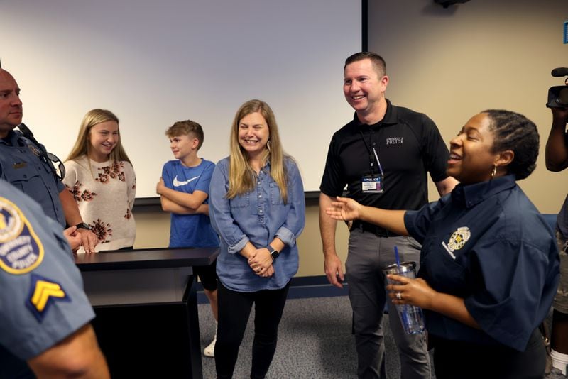 Gwinnett County Police officer Doug Loomis, center, and his wife Ashley talks with 911 dispatcher Brandy Britton as Loomis thanks first responders that helped him after going into cardiac arrest at the Gwinnett County Justice and Administration Center, Wednesday, September 21, 2022, in Lawrenceville. Also shown are the Loomis’ two children, Mary and Jack (Jason Getz / Jason.Getz@ajc.com)