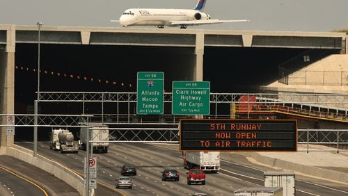 060527 - RIVERDALE, GA: A Delta plane rolls over the 5th runway bridge as cars continue to move on Interstate 285 on Saturday, 5/27/06. Today was the first day of runway was open to air traffic .PHOTO BY JOHNNY CRAWFORD/AJC STAFF