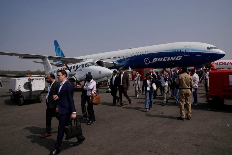 FILE - Visitors pass a Boeing 777X aircraft displayed during the 'Wings India 2024" biennial aviation event at Begumpet airport in Hyderabad, India, Jan. 18, 2024. In the latest round of their decades-long battle for dominance in commercial aircraft, Europe's Airbus has established a clear sales lead over Boeing as the American company deals with the fallout from manufacturing troubles and ongoing safety concerns. (AP Photo/Mahesh Kumar A., File)
