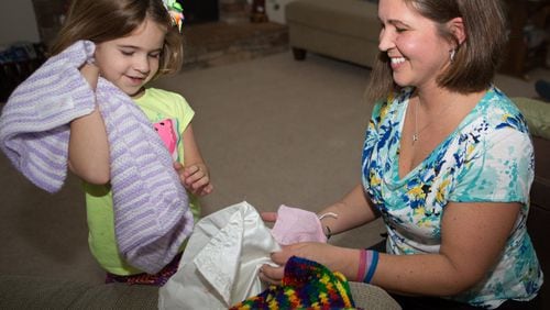 Andrea Kennedy(right) shows her daughter Olivia (age 6) blankets that they brought home from the hospital after their daughter Vivian died on the day she was born. The shocking event plunged Andrea into profound sadness and confusion. Kennedy now has three children, is active in her church and volunteers in her community, but baby Vivian is always in her thoughts. Kennedy teaches grief classes for GriefShare, a national faith-based support group that combines video tutorials with scripture readings and journaling and talk therapy. (Photo by Phil Skinner)