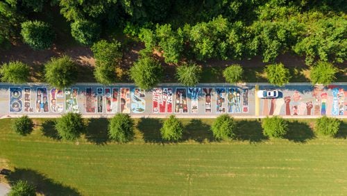 An aerial photo shows a giant colorful mural on the driveway of Drew Charter School Junior/ Senior Academy on Tuesday, Aug. 24, 2021. The mural was designed, executed and installed by students and community members with the help of local artists. (Hyosub Shin / Hyosub.Shin@ajc.com)