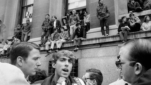 FILE - Mark Rudd, a leader of the student protest at Columbia University in New York City, is interviewed outside Low Memorial Library, background, April 25, 1968, which has been occupied by students since the previous day. Rudd said the purpose of the protest was to "hit at" what he claimed was the university's policy of "racism and support for imperialism." (AP Photo/File)