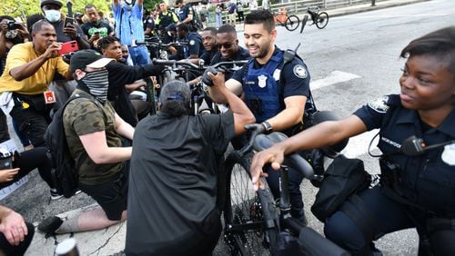 Atlanta Police Officer J. Nguyen (center) and his fellow cops knee-down in a symbolic gesture of solidarity with demonstrators, and exchange handshakes and fist bumps with protesters at Centennial Olympic Park on June 3, 2020 — the sixth consecutive day of protests in Atlanta against police brutality and racism. (Hyosub Shin / Hyosub.Shin@ajc.com)