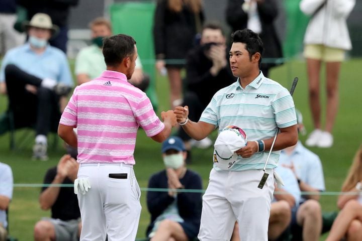 April 10, 2021, Augusta: Xander Schauffele, left, and Hideki Matsuyama give each other a fist bump as they finish their third round during the Masters at Augusta National Golf Club on Saturday, April 10, 2021, in Augusta. Curtis Compton/ccompton@ajc.com