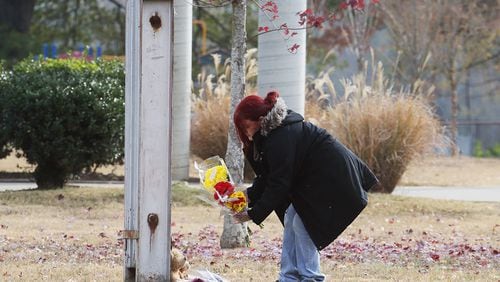 Michelle Hutto places flowers near a flagpole outside Woodmore Elementary School. Her son was friends with one of the children killed in a Chattanooga bus crash and her nephew was injured. (BOB ANDRES / bob.andres@ajc.com)