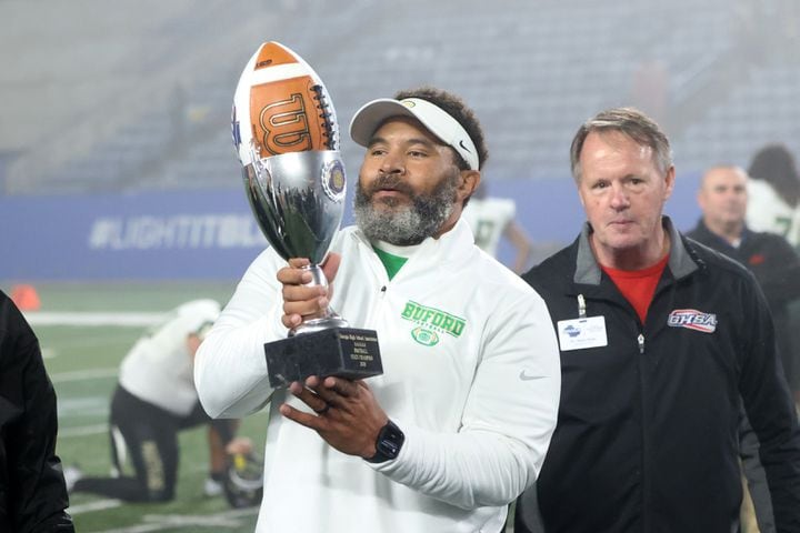 Buford head coach Bryant Appling hoists the trophy after their 21-20 win against Langston Hughes during the Class 6A state title football game at Georgia State Center Parc Stadium Friday, December 10, 2021, Atlanta. JASON GETZ FOR THE ATLANTA JOURNAL-CONSTITUTION
