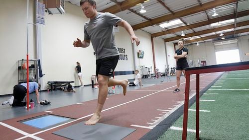 In this June 22, 2017, photo, lacrosse player Frankie Hattler performs a single leg dynamic stabilization landing test, which gives insight for the left side versus the right side of the body and can be used for later stages of returning to playing, as Sparta Science coach Kayla Sowinski watches in Menlo Park, Calif., Thursday, June 22, 2017. To keep players on the field instead of in the operating room and to maximize their ability when healthy, more and more pro and college sports teams are turning to technology. (AP Photo/Jeff Chiu)