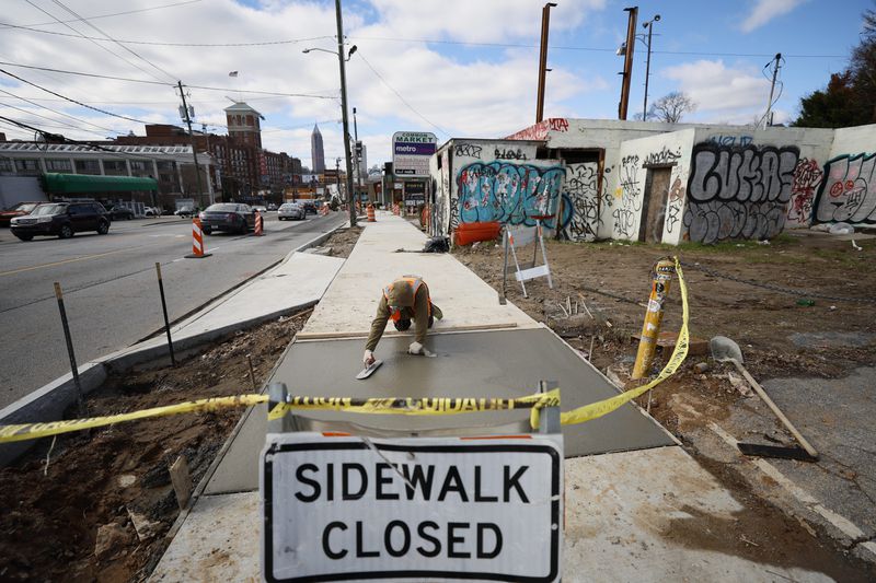 A construction worker is seen repairing the sidewalk on Ponce de Leon in front of an abandoned business on Monday, January 23, 2022. Miguel Martinez / miguel.martinezjimenez@ajc.com