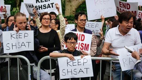 Activists hold signs during a protest last week against New York City’s plan to revamp admissions to specialized high schools. Asian students are now overrepresented at the schools, but a plan offered by Mayor Bill de Blasio would  give more spots to black and Hispanic students.