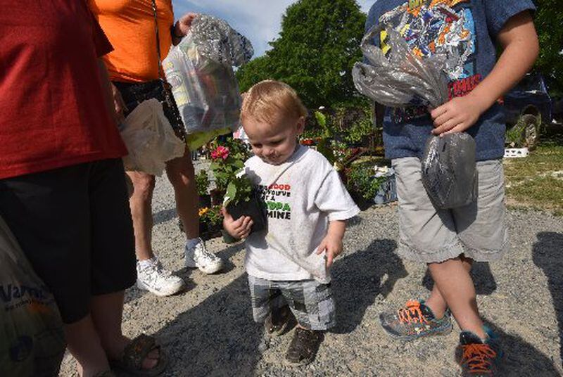 Hunter Rimpley, 1, holds a plant at Wantip Campbell's booth at Trade Days. HYOSUB SHIN / HSHIN@AJC.COM