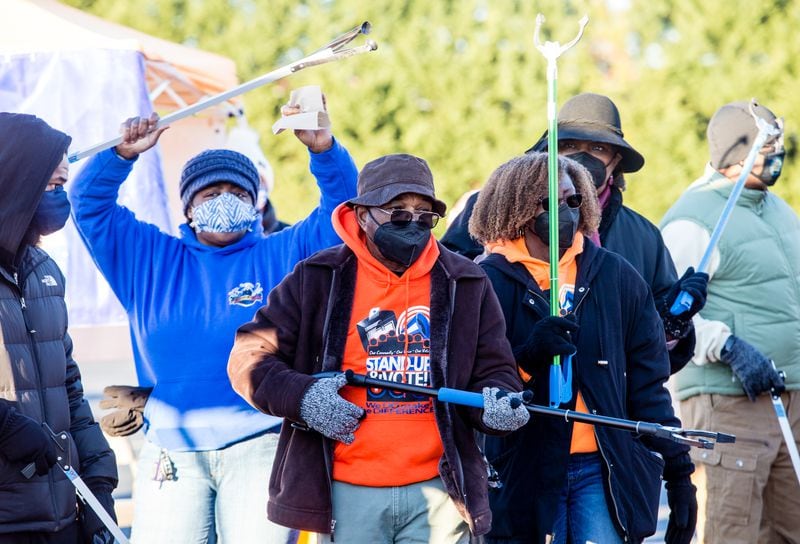 Volunteers, including Horace Cooper, in orange, of Fairburn, get warmed up and play their trash pick up tools like musical instruments on Monday, Jan. 18, 2021, at Impact Church. (Jenni Girtman for The Atlanta-Constitution)