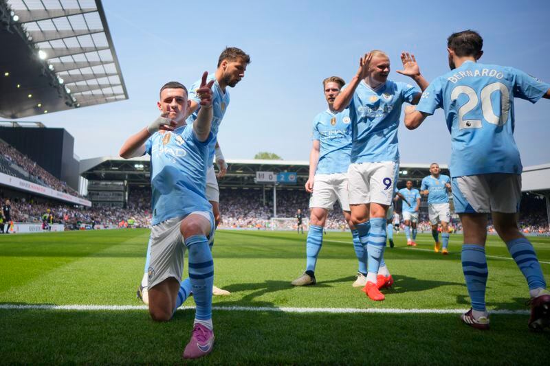 Manchester City's Phil Foden, left, celebrates with teammates after scoring his side's second goal during the English Premier League soccer match between Fulham and Manchester City at the Craven Cottage Stadium in London, Saturday, May 11, 2024. (AP Photo/Kirsty Wigglesworth)