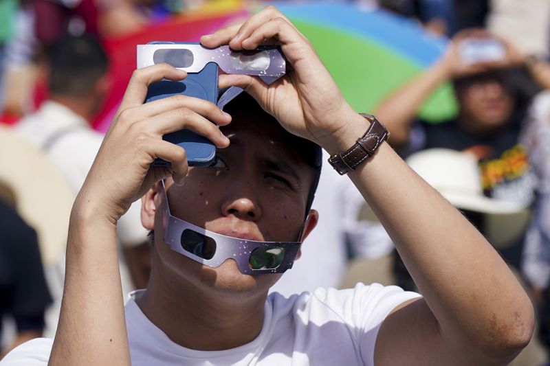 A man takes photos of a total solar eclipse in Mazatlan, Mexico, Monday, April 8, 2023. (AP Photo/Fernando Llano)