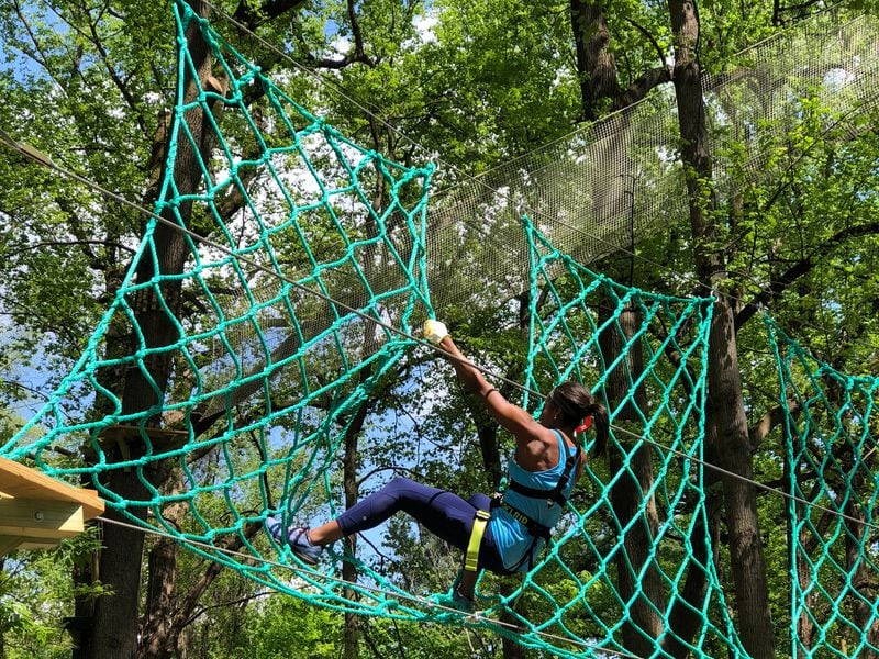 Participant tests her strength and fear of heights on this vertical cargo net.