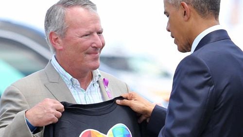 President Barack Obama looks at a T-shirt that was presented to him by Orlando, Fla. Mayor Buddy Dyer upon the president's his arrival at Orlando International Airport, Thursday, June 16, 2016, in Orlando, Fla. Obama is in Orlando today to pay respects to the victims of the Pulse nightclub shooting and meet with families of victims of the attack. (Joe Burbank/Orlando Sentinel via AP)