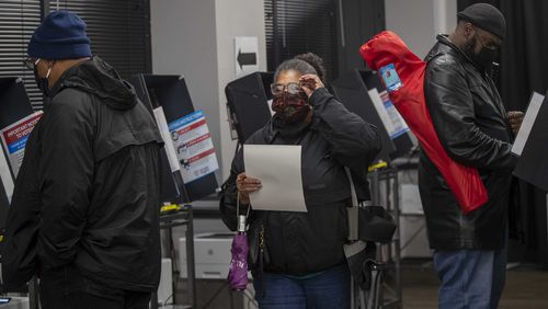 Cobb County resident Darlene Hines, 63, adjusts her foggy glasses as she prepares to cast her ballot  in December during early voting at the Cobb County Elections and Voter Registration Office in Marietta. (Alyssa Pointer / Alyssa.Pointer@ajc.com)