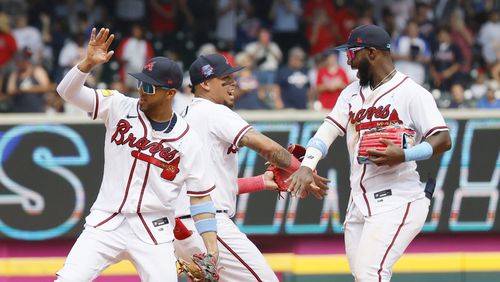 Braves center fielder Michael Harris II (right) shakes hands with shortstop Orlando Arcia as left fielder Edwin Rosario reacts after their team defeated the Colorado Rockies 14-6 at Truist Park. The Braves swept the Rockies in a four-game series. Miguel Martinez / miguel.martinezjimenez@ajc.com