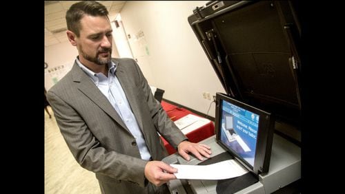 Jeb Cameron with Election Systems & Software demonstrates the paper ballot voting machines at Rockdale County Board of Elections in Conyers, where a test run of the machines was conducted during November’s elections. STEVE SCHAEFER / SPECIAL TO THE AJC