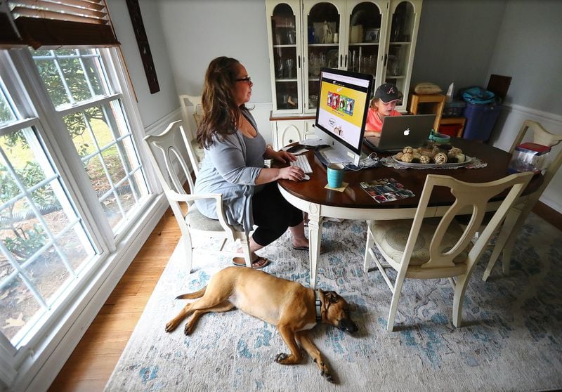 Sandra Gurley juggles decisions about branding as well as two children, working in isolation from the dining room of her Marietta home with daughter Cassidy, 8, and the family dog Tessa on Tuesday, April 7, 2020. Gurley is the director of brands for High Road Ice Cream. Her son Liam (not pictured) is 13. (Photo: Curtis Compton  / ccompton@ajc.com)