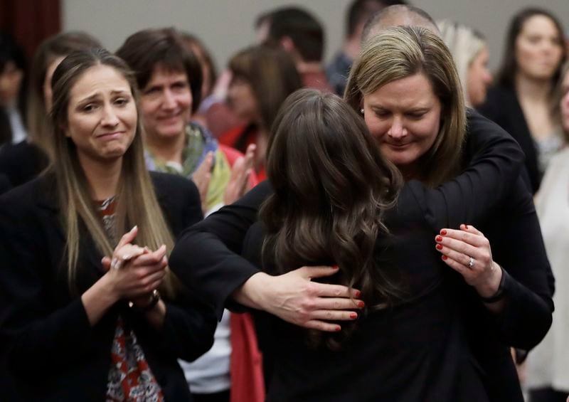 FILE -In this Jan. 24, 2018, file photo, victims react and hug Assistant Attorney General Angela Povilaitis after Larry Nassar was sentenced by Judge Rosemarie Aquilina to 40 to 175 years in prison during a sentencing hearing in Lansing, Mich. The U.S. Justice Department announced a $138.7 million settlement Tuesday, April 23, 2024, with more than 100 people who accused the FBI of grossly mishandling allegations of sexual assault against Larry Nassar in 2015 and 2016, a critical time gap that allowed the sports doctor to continue to prey on victims before his arrest. (AP Photo/Carlos Osorio, File)