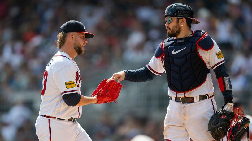 Atlanta Braves catcher Travis d'Arnaud hands the ball to relief pitcher A.J. Minter in the eighth inning of a baseball game against the Pittsburgh Pirates, Sunday, Sept. 10, 2023, in Atlanta. (AP Photo/Hakim Wright Sr.)