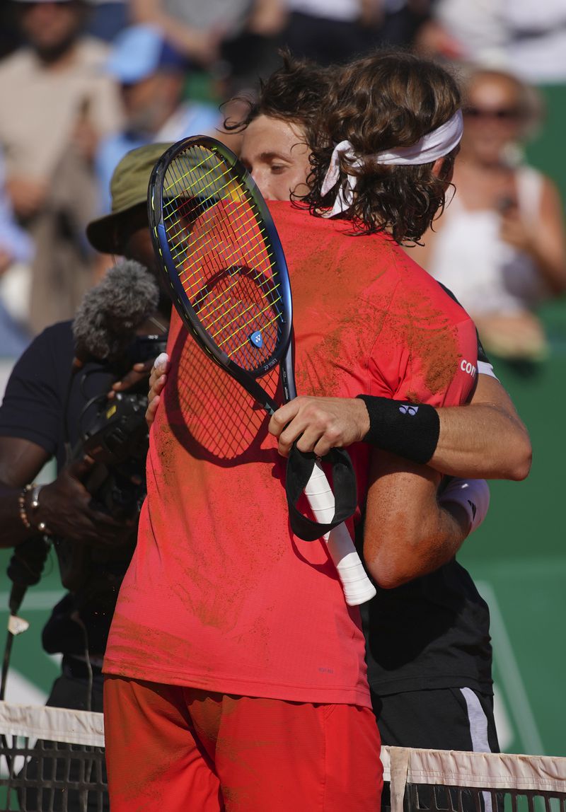 Stefanos Tsitsipas of Greece, front, embraces Casper Ruud of Norway after winning the Monte Carlo Tennis Masters final match 6-1, 6-4 in Monaco, Sunday, April 14, 2024. (AP Photo/Daniel Cole)