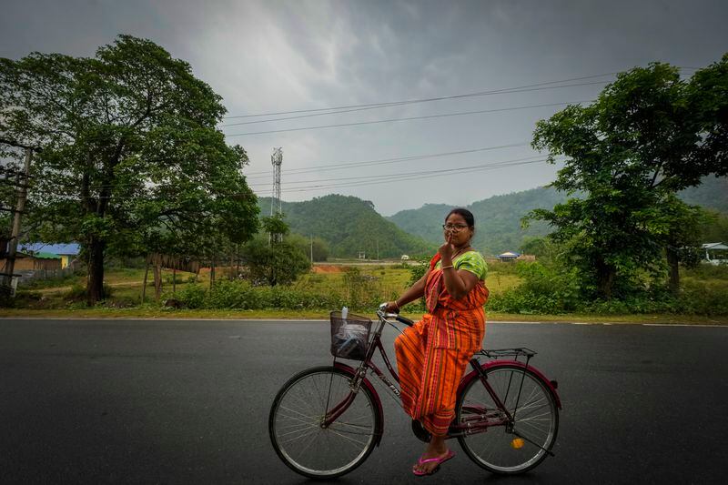 Purnima Boro, 30, a Bodo tribal woman in traditional attire riding a bicycle shows the indelible ink mark on her index finger as she returns after casting her vote during the third phase of general election on the outskirts of Guwahati, India, Tuesday, May 7, 2024. (AP Photo/Anupam Nath)