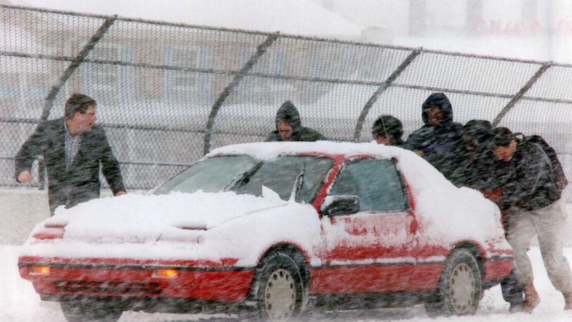 This file photo from March 13, 1993, shows good Samaritans lending a hand to a stuck motorist. That day was the snowiest in the history of Cobb County.