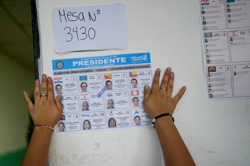 An electoral worker sticks a ballot on a polling station's wall to use as sample during a general election in Panama City, Sunday, May 5, 2024. (AP Photo/Matias Delacroix)