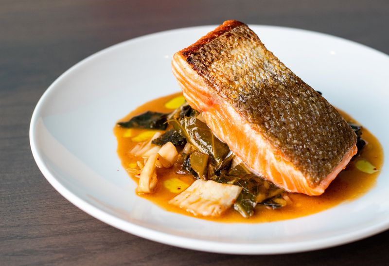 Seared salmon with kimchi-collard greens at Noona combines sophistication with Asian and American Southern elements. CONTRIBUTED BY HENRI HOLLIS