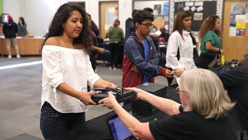 Cross Keys junior Lesly Chavez receives a Chromebook laptop from DeKalb County Schools information technology employee Mary Isle during the Chromebook distribution at Cross Keys High School Thursday Sept. 13, 2018. Before the project launched, about 30 percent of students lacked internet access, while 35 percent did not have a home computer. (JASON GETZ/SPECIAL TO THE AJC)