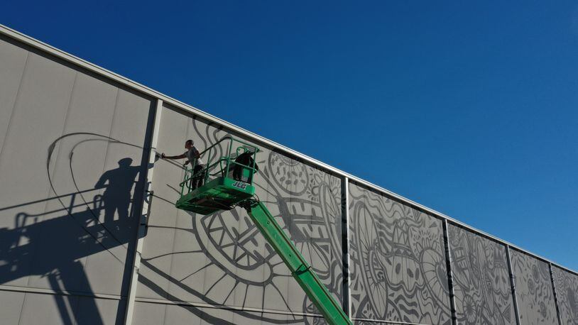 "Black Panther" artist Brandon Sadler paints the side of the 118,000-square-foot Trilith soundstage in Fayetteville. The mural, which eventually covered all three sides of the building, is one of the largest in Georgia, Trilith leaders say.