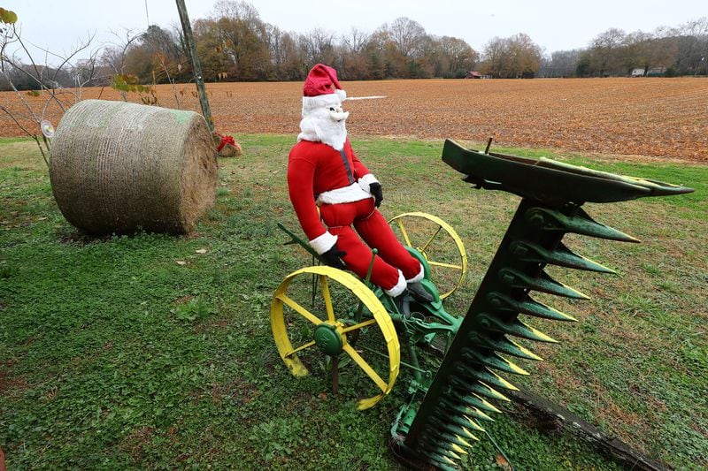 A Santa sits on an antique piece of farm equipment next to a recently harvested field along Atlanta Highway in the tiny historic town of Rutledge on Wednesday, Dec 8, 2021.   “Curtis Compton / Curtis.Compton@ajc.com”`