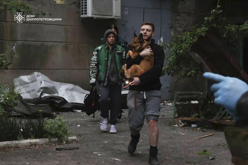In this photo provided by the Ukrainian Emergency Service, local residents leave an apartment building, damaged after a Russian attack in Dnipro, Ukraine, Friday, April 19, 2024. (Ukrainian Emergency Service via AP Photo)