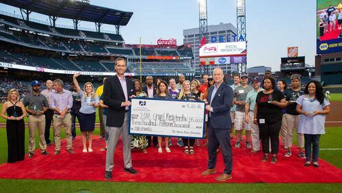 Braves president Derek Schiller, left, and Adam Zimmerman, Braves senior vice president of marketing, hold a giant check that reads "2018 Grant Recipients," which isn't how checks work, but you get the idea.