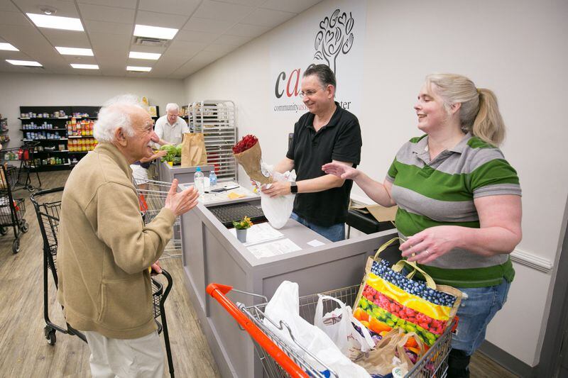 In 2018, Community Assistance Center volunteers Mort Epstein, center, and Lori Proctor, right, helped customer Alexander Boguslavskiy check out at the food pantry on Roswell Road in Sandy Springs  (JASON GETZ/SPECIAL TO THE AJC)