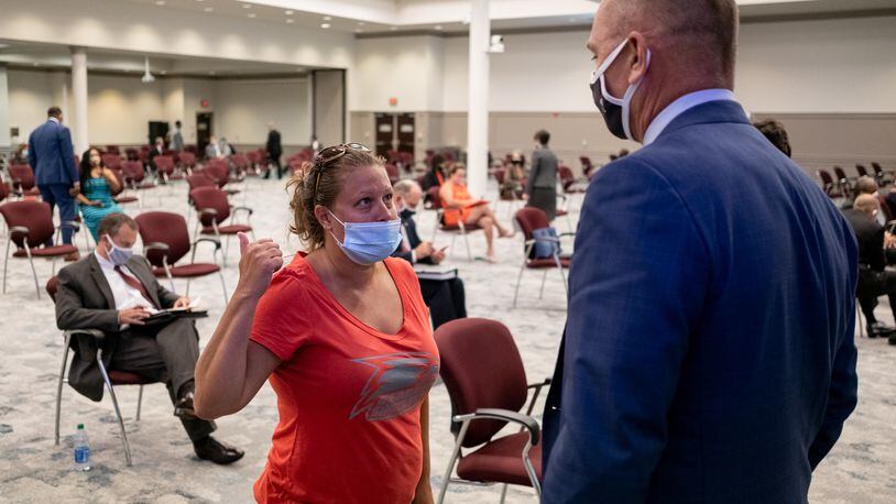 Mary Williams, a parent who is opposed to mandatory face mask requirements, talks with Gwinnett County Public Schools board member Steven Knudsen before the start of the regular board meeting in Suwanee on  July 16. Ben Gray for the Atlanta Journal-Constitution