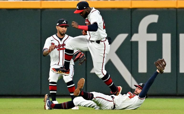 Atlanta Braves shortstop Dansby Swanson (7) makes an over the shoulder catch of the popup by Philadelphia Phillies’ J.T. Realmuto as Atlanta Braves right fielder Ronald Acuna (13) leaps over him during the sixth inning of game two of the National League Division Series at Truist Park in Atlanta on Wednesday, October 12, 2022. (Hyosub Shin / Hyosub.Shin@ajc.com)