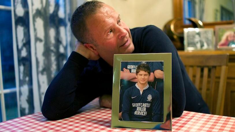Peter Robinson with a photo of his son Benjamin who died at 14 years of age from multiple hits to the head during a rugby match, at home in Roslin, Scotland, Oct. 28, 2015. The efforts of Robinson and British scientist Willie Stewart have led to Scotland adopting a concussion protocol that applies not just to rugby but to all sports at all levels, from scholastic games to adult leagues, and is now seen as a model for other countries. (Kieran Dodds/The New York Times)