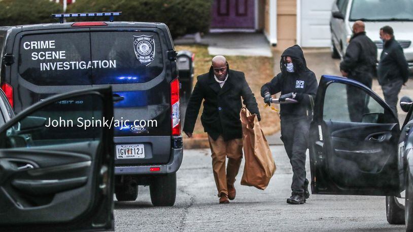 DeKalb County homicide detectives and crime scene investigators collect evidence Thursday morning outside a home on Deep Shoals Circle where a man's body was found shot multiple times.
