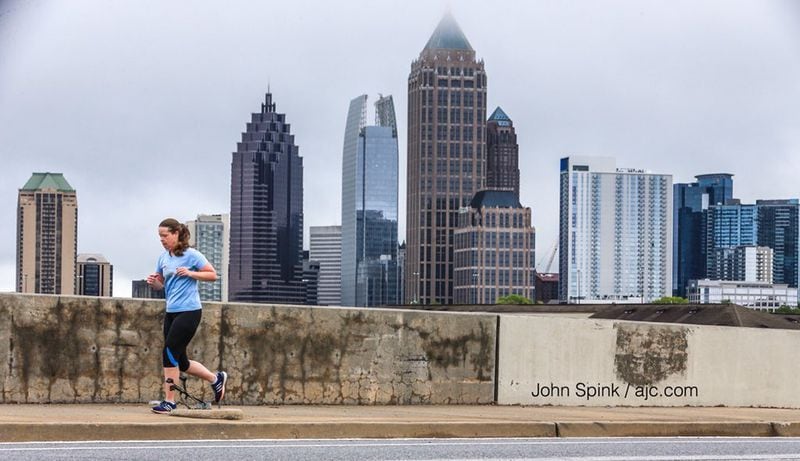 It was cloudy but dry on Denise Black’s run on 17th Street near Northside Drive on Monday. JOHN SPINK / JSPINK@AJC.COM
