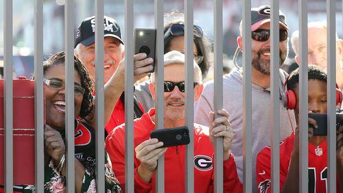 Georgia fans angle for a view and snap photos through the fence while the Georgia official team photo is taken at Rose Bowl Stadium on Sunday, December 31, 2017, in Pasadena.    Curtis Compton/ccompton@ajc.com